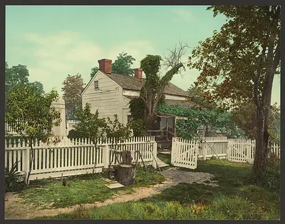 White clapboard house behind a white picket fence