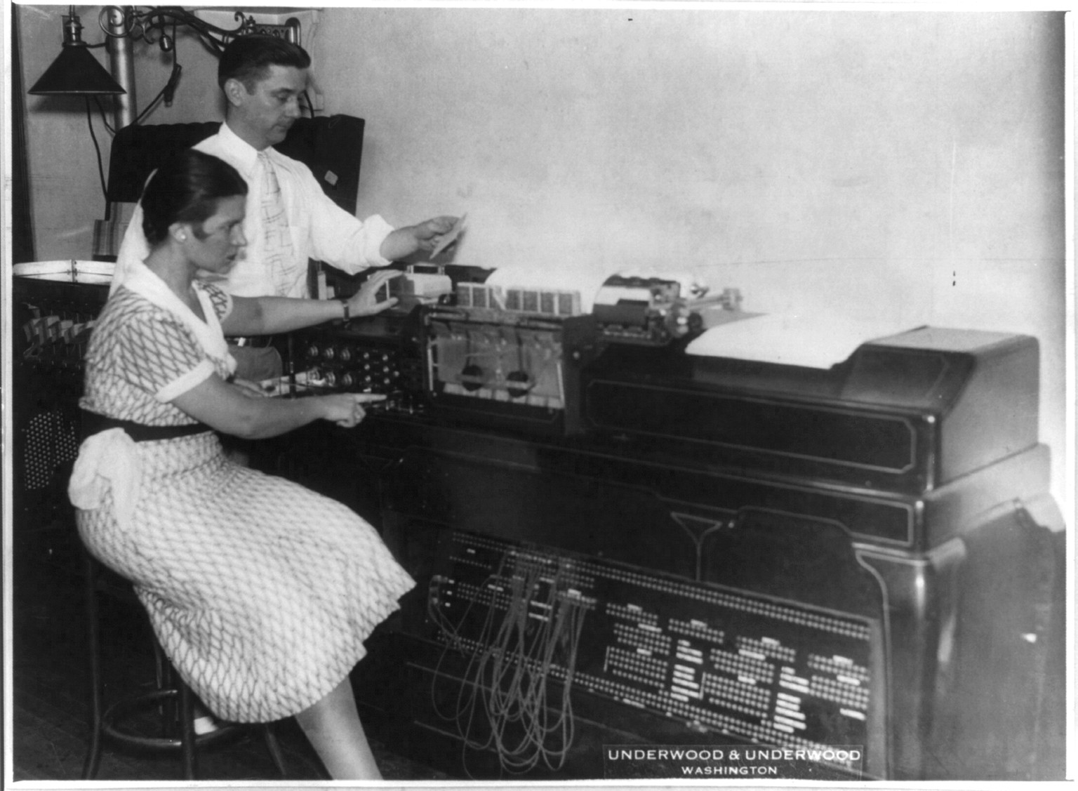 [Machines being used in automobile travel analysis at federal agency in Wash., D.C.: Miss Elizabeth Woodward with man using electric tabulating machine], 1932 Aug. 15. — historic photograph