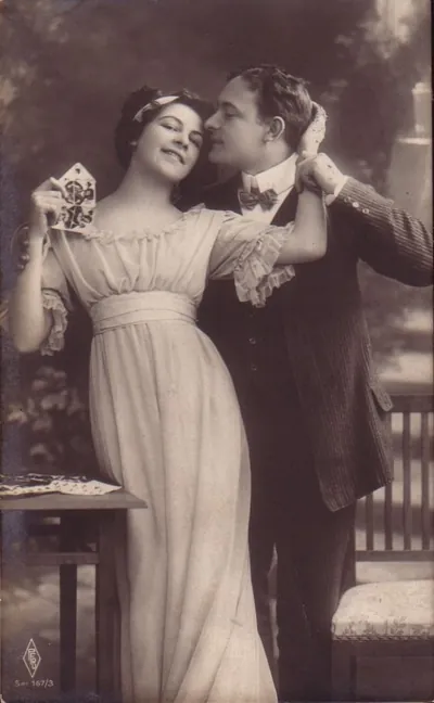 Sepia postcard of a couple, woman holding playing cards