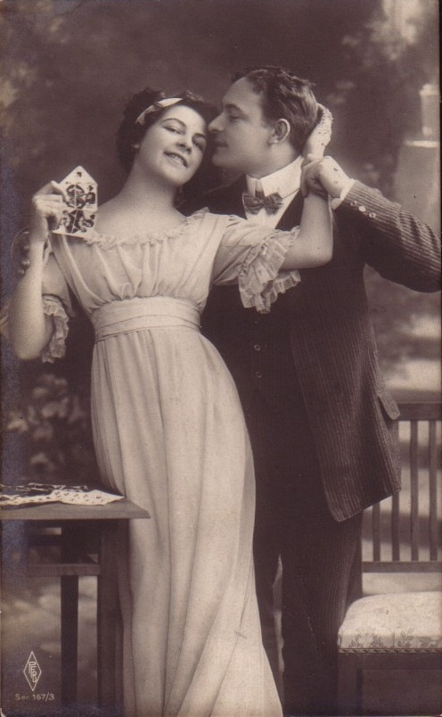 Sepia postcard of a couple, woman holding playing cards — vintage postcard