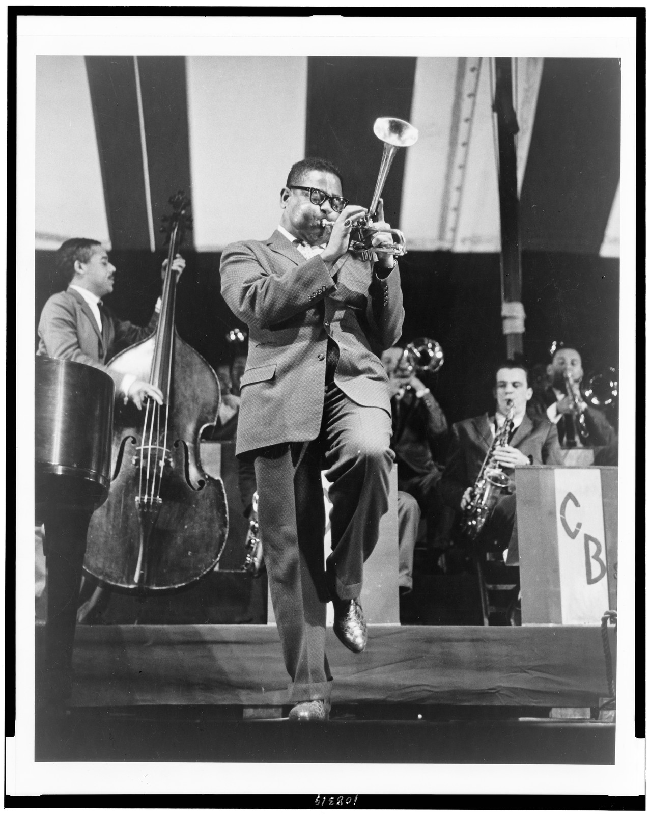 [Jazzman Dizzy Gillespie, full-length, standing, facing right, playing horn on stage] — historic photograph