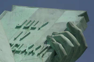 Close-up of Statue of Liberty hand and tablet in green copper