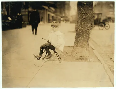 Young boy on a small bicycle on a city sidewalk