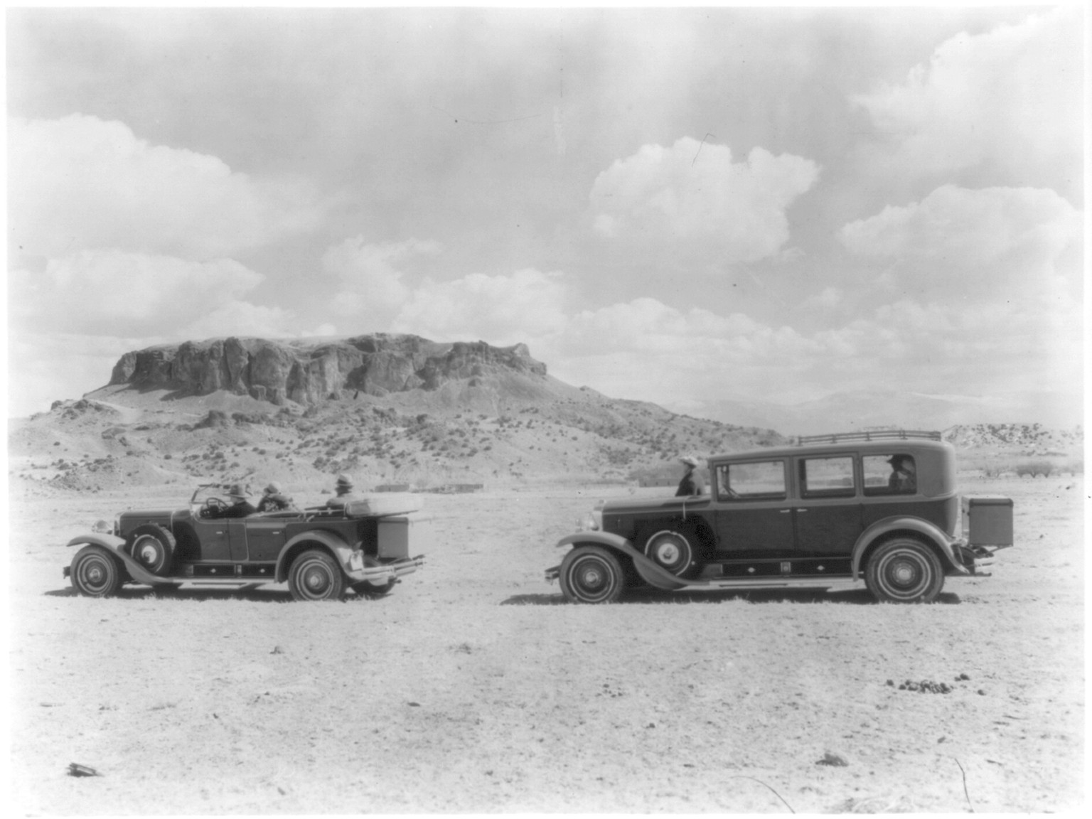 [Side view of two automobiles, one a convertible, with Black Mesa, New Mexico in the background], [ca. 1924] — historic photograph