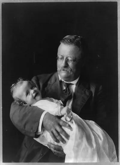 [Theodore Roosevelt, half-length portrait, seated, looking down, holding his grandchild, Kermit Roosevelt, Jr.]
