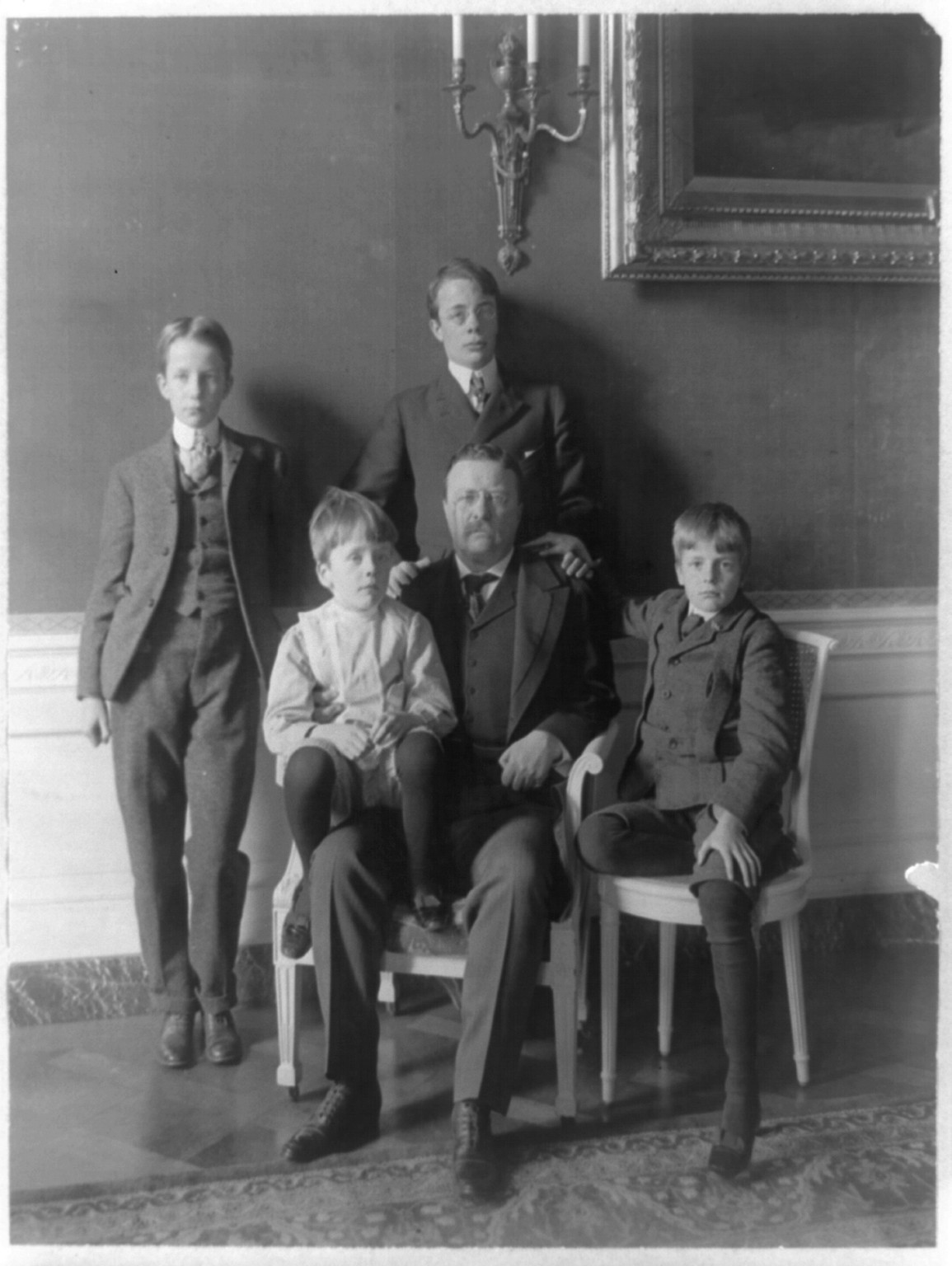 [Theodore Roosevelt, full-length portrait, seated, facing front, with his four sons posed around him], c1904. — historic photograph