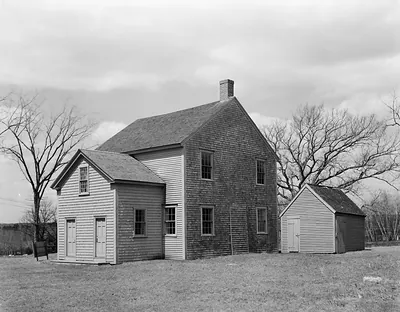 Shingled colonial house with outbuilding, black and white photograph