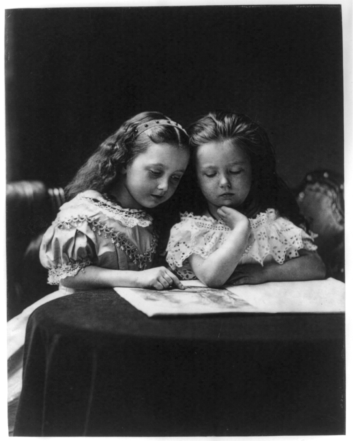 [Two small girls reading at small round table], 1869 — historic print