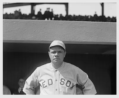 Baseball player in Red Sox uniform standing in a dugout