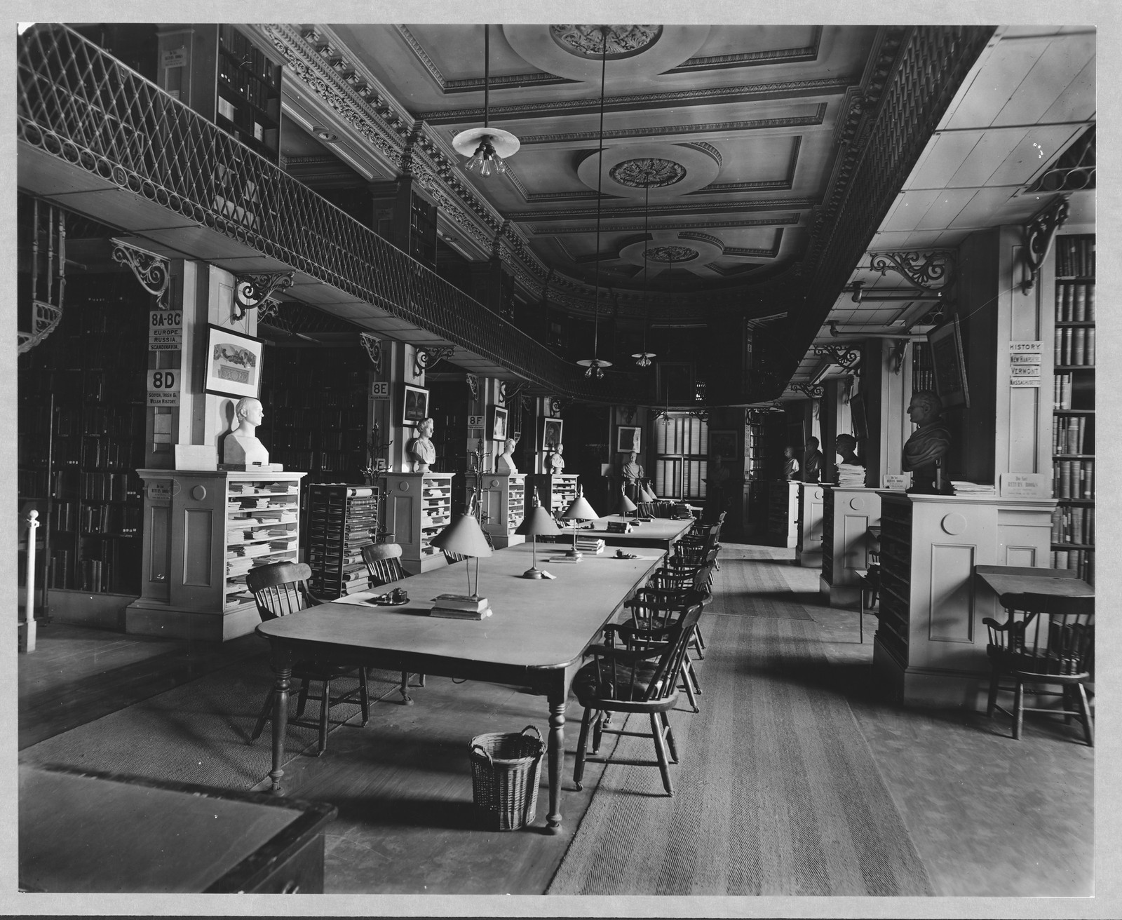 Interior of a library with busts, galleries and reading tables — historic image