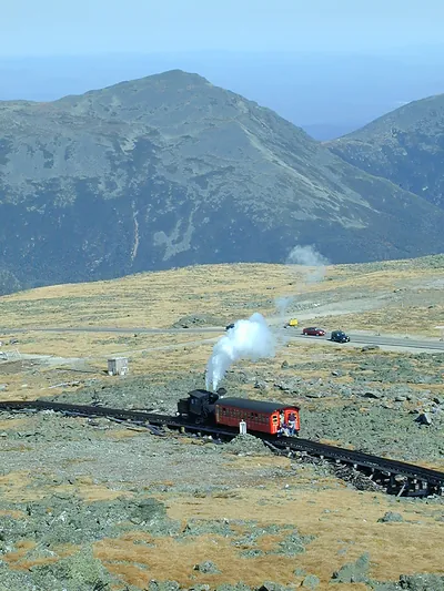 Steam cog railway train on mountain tracks with steam