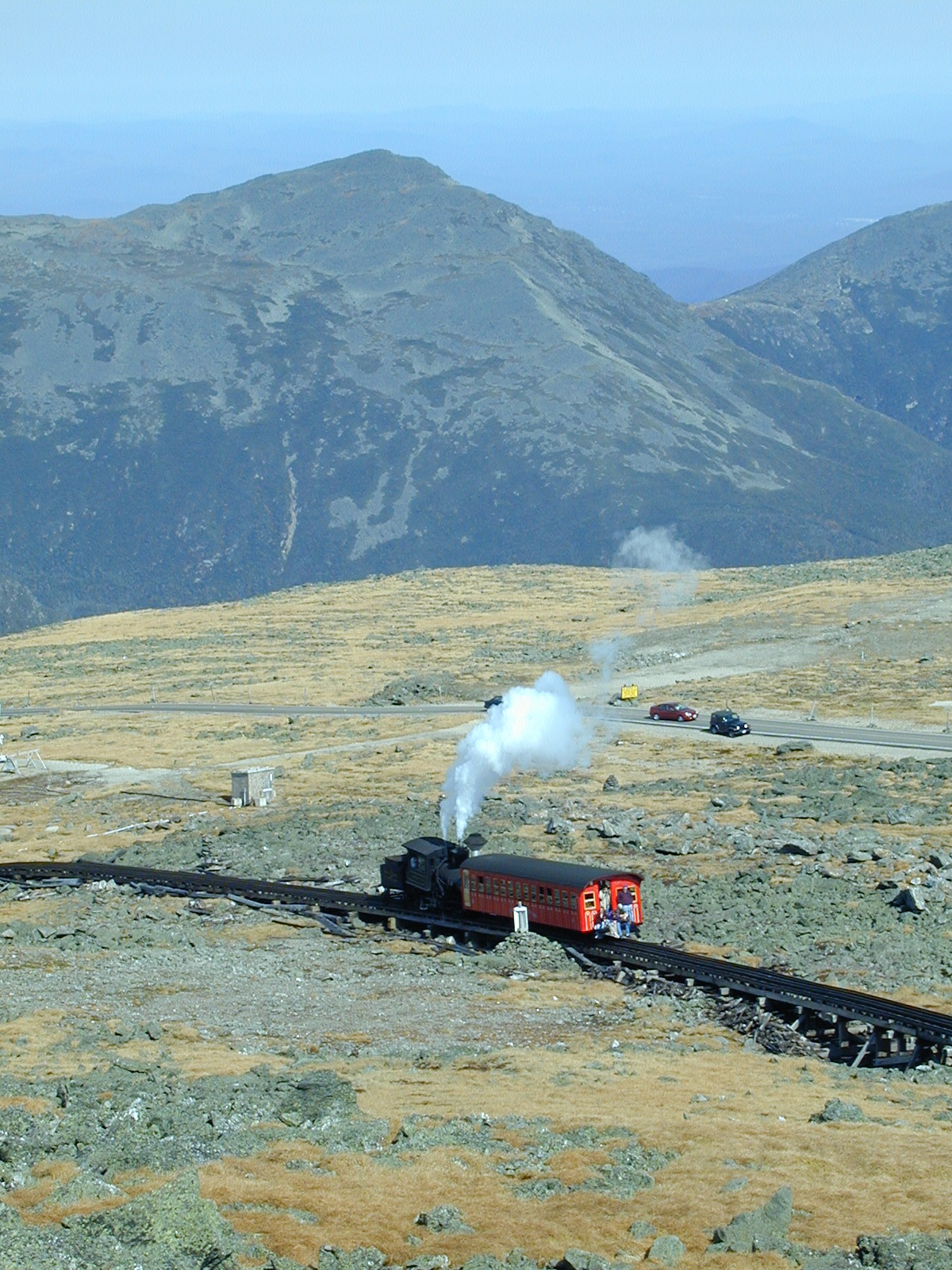 Steam cog railway train on mountain tracks with steam — historic image