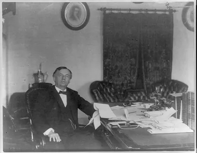 John Wanamaker, 1838-1922, three-quarter length portrait, seated, at desk, facing right