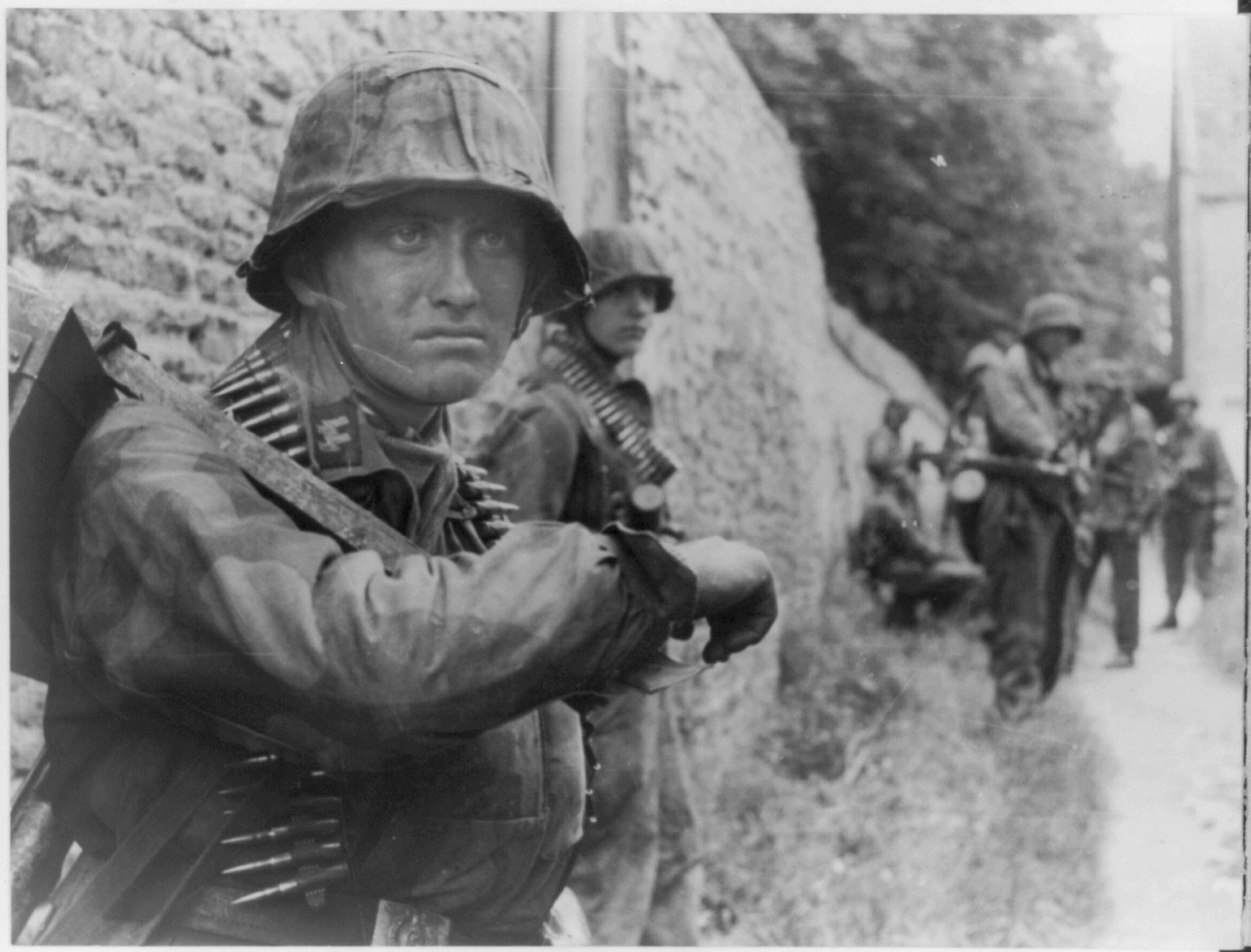 [Waffen SS soldier standing against a wall, wearing bandolier of bullets] — historic photograph
