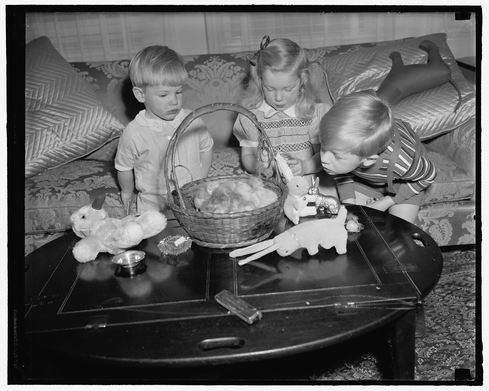 Woodring children get preview of their Easter Basket. Washington, D.C., April 5. The Woodring children, sons and daughter of the Secretary of War and Mrs. Harry H. Woodring, were given a preview today of what to expect from the Easter Bunny on Sunday. The children, left to right: Cooper, Melissa and Marcus Coolidge are expected to roll their eggs at the White House on Easter Monday, 4/5/39, 1939 April 5. — historic photograph