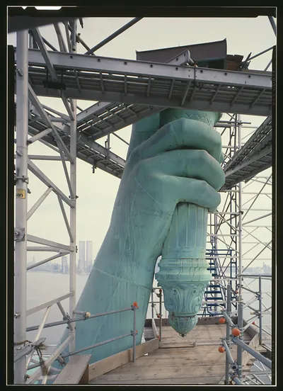 Statue of Liberty hand gripping torch on scaffolding