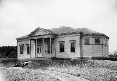 Classical wooden building with columned front porch