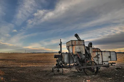 Rusted antique threshing machine on open prairie