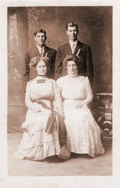 Two couples posing in a formal sepia studio portrait