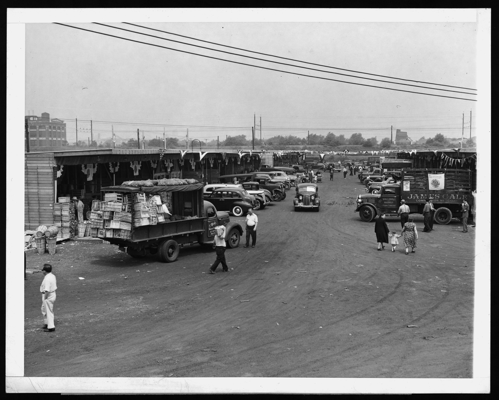 Trucks and crates at an outdoor produce market — historic image