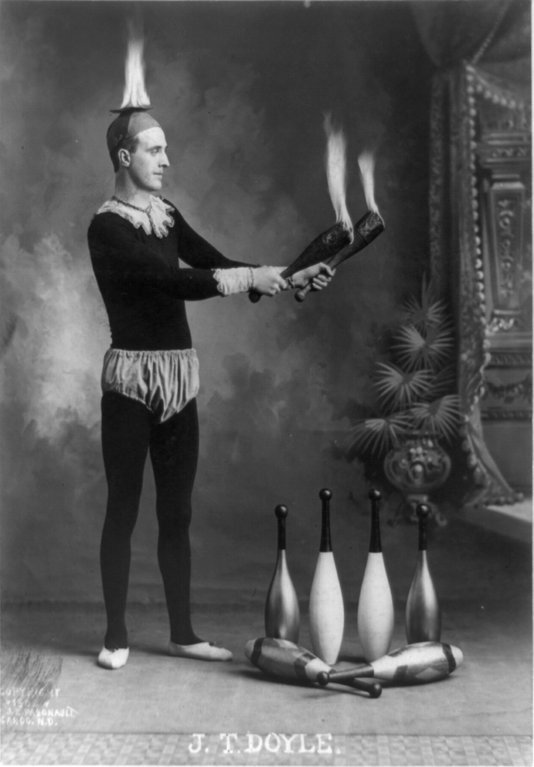 J.T. Doyle [holding 2 burning juggling clubs], c1902. — historic photograph