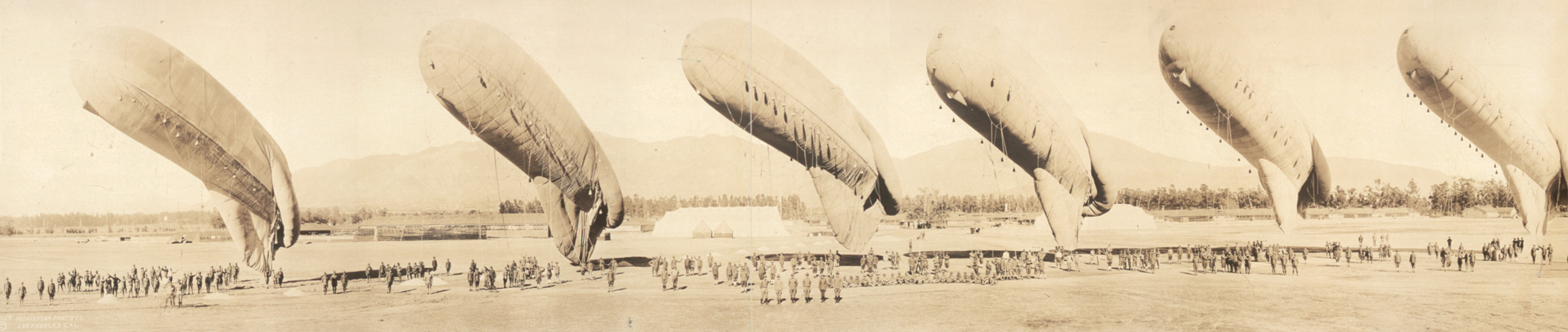 Several airships being inspected on a field before a crowd — historic image