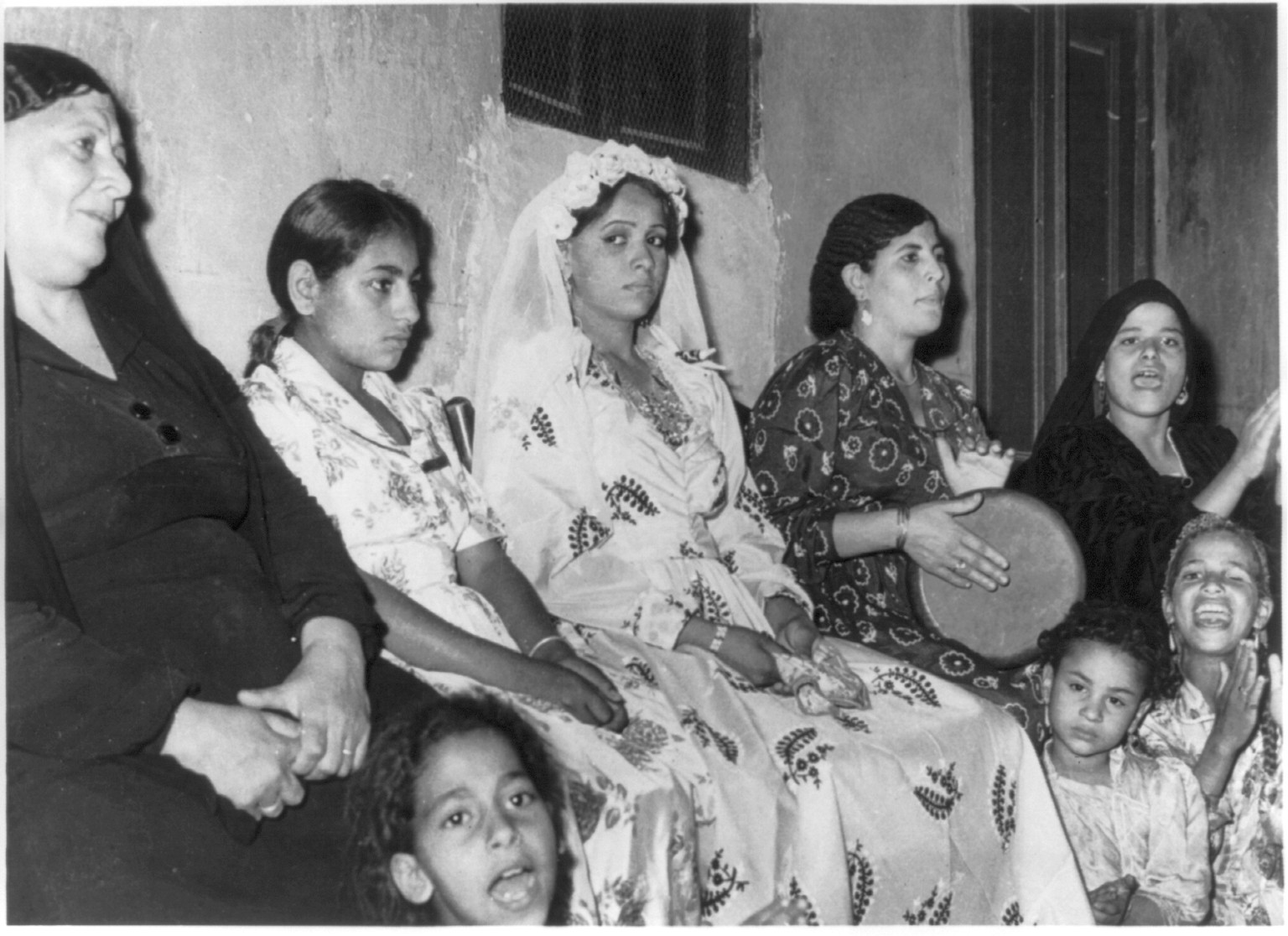 A bride dressed up for her wedding while her friends are happily singing, [United Arab Republic], [no date recorded on caption card] — historic photograph