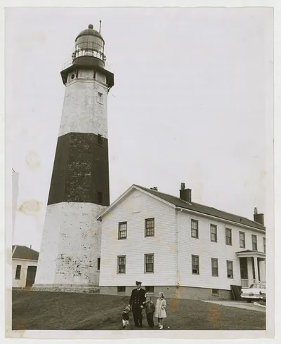 Man in uniform and children before a striped lighthouse