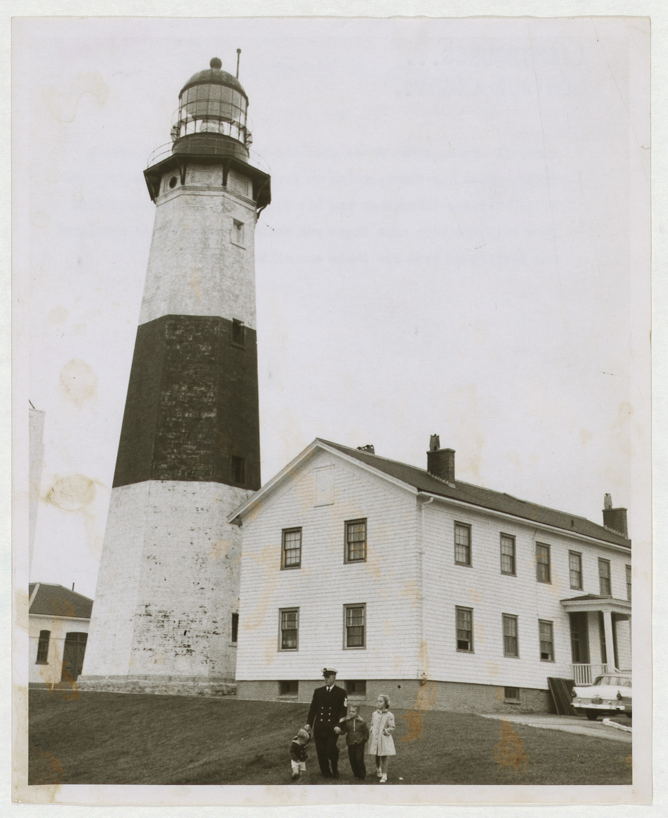 Man in uniform and children before a striped lighthouse — historic image