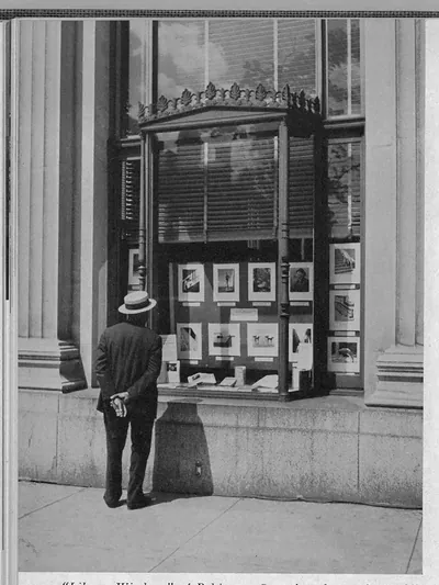 Man viewing a library display window with framed photographs