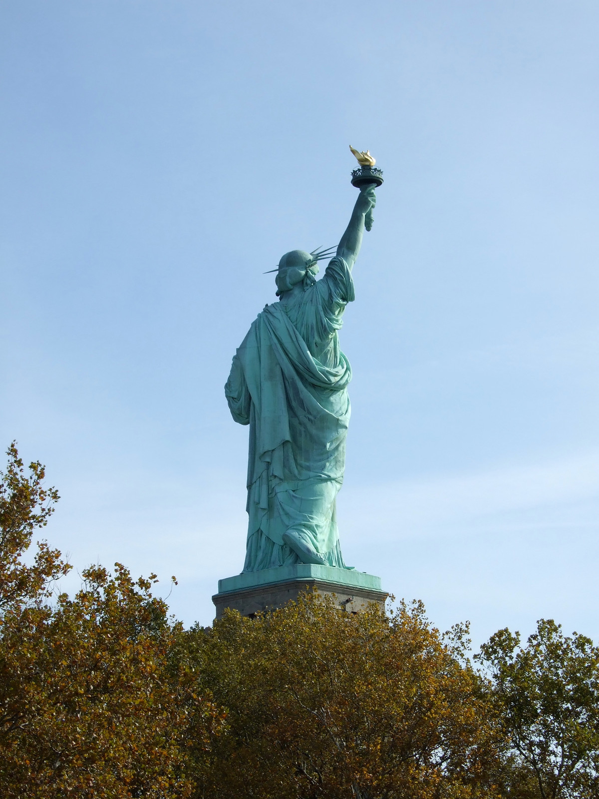 Statue of Liberty seen from behind against blue sky — historic image