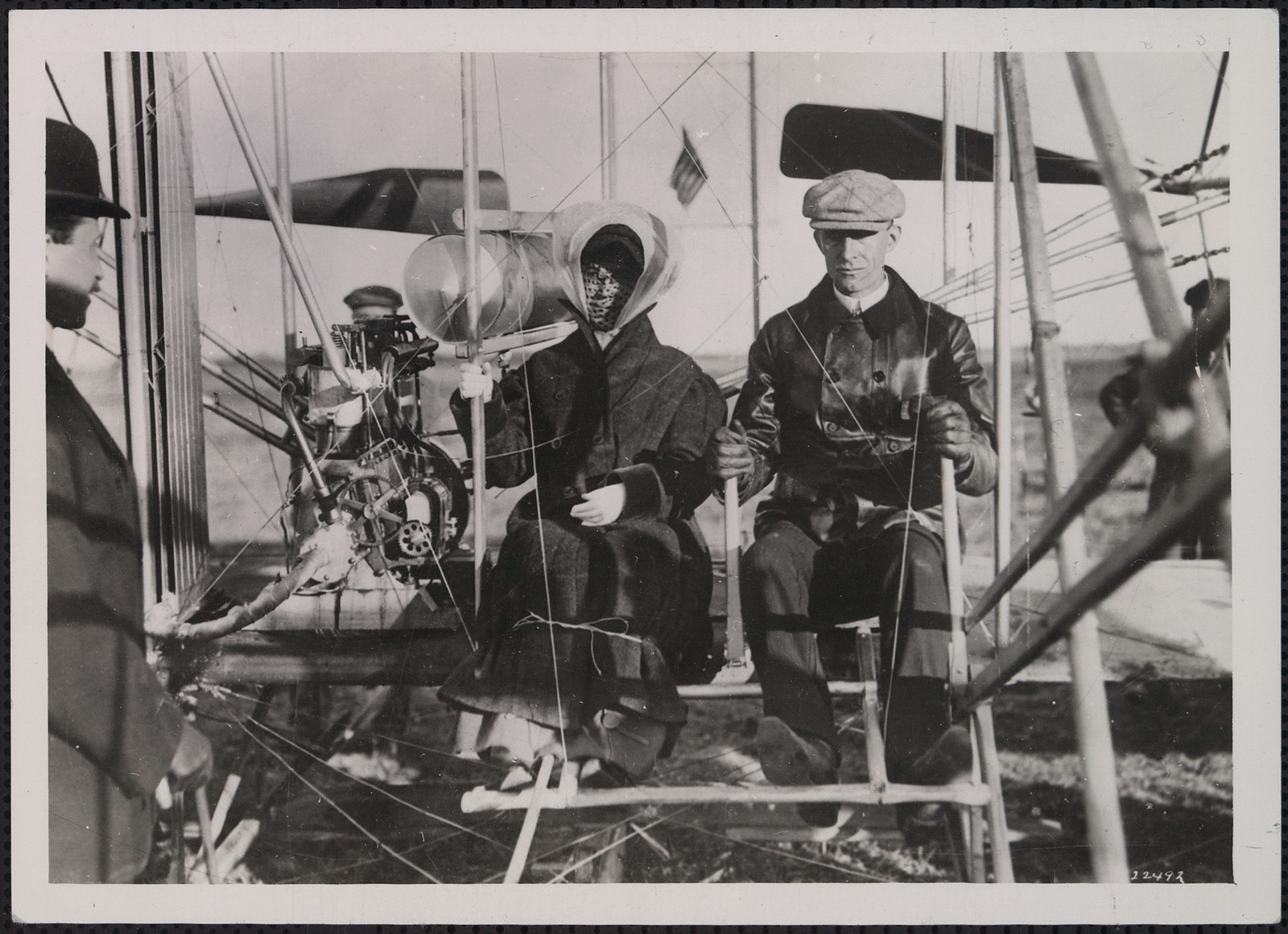 Two people seated in an early biplane, black and white photograph — historic photograph