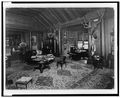 [Library(?) at Theodore Roosevelt's home, Sagamore Hill, Long Island, with two elk heads on wall]