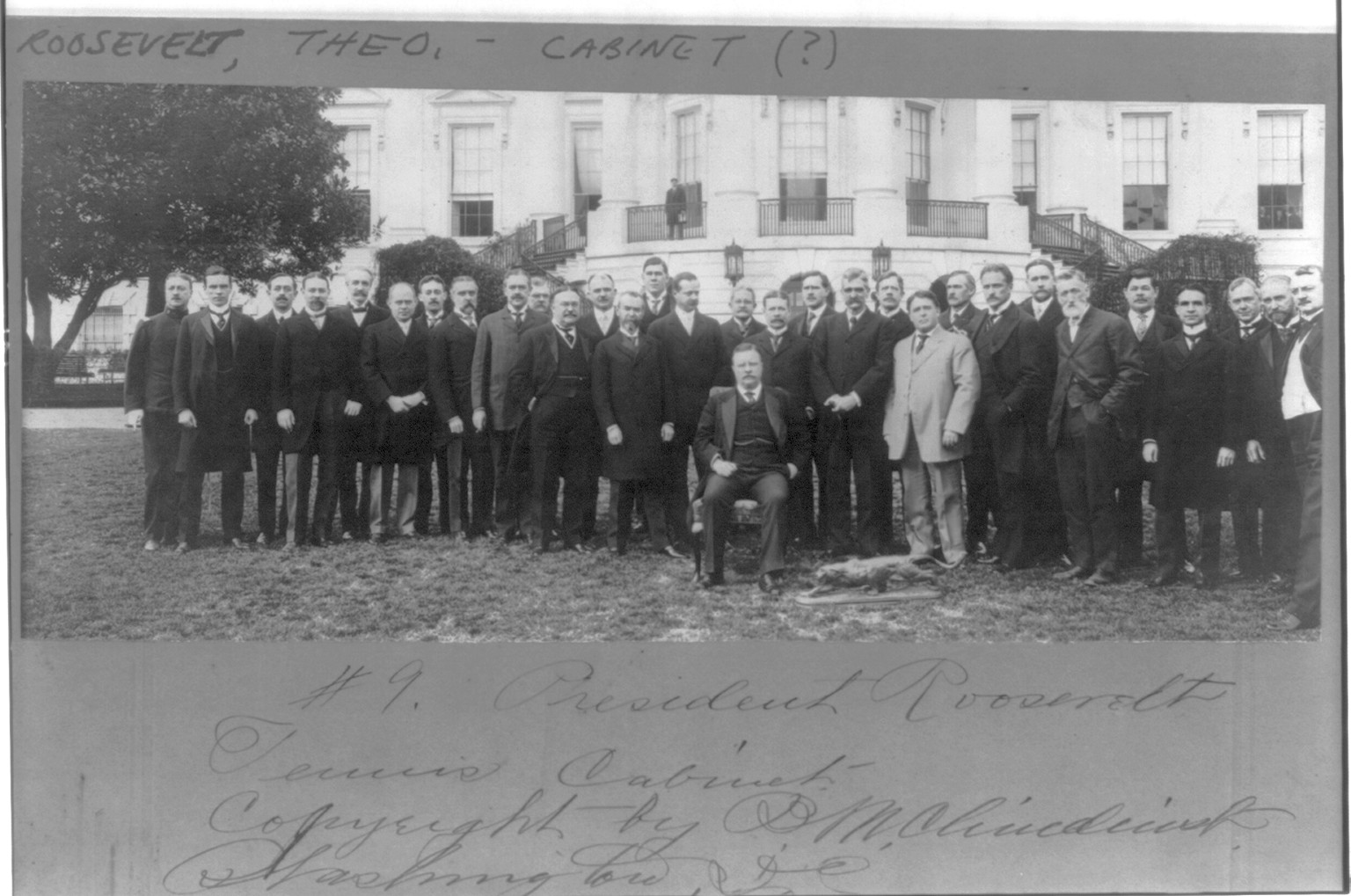 [Theodore Roosevelt, full, seated, on White House lawn flanked by Tennis Cabinet" of 30 men]" — historic photograph