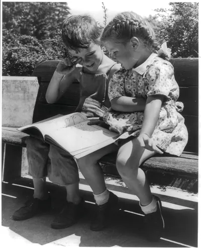 [Boy and girl on bench looking at book, Greenbelt, Maryland]