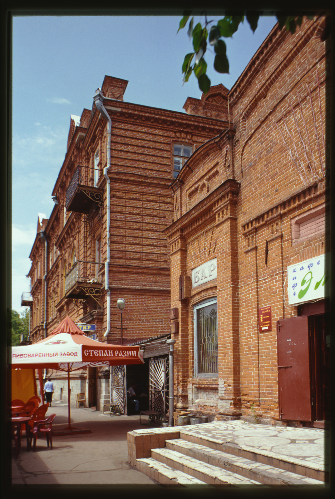 Brick street building with BAR and café signs, beer umbrella — historic image