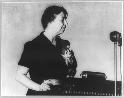 [Eleanor Roosevelt, half length, facing right, standing before microphone]