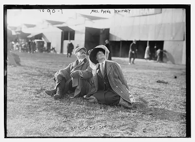Mrs. Payne Whitney with unidentified gentleman seated on flying field of aviation meet