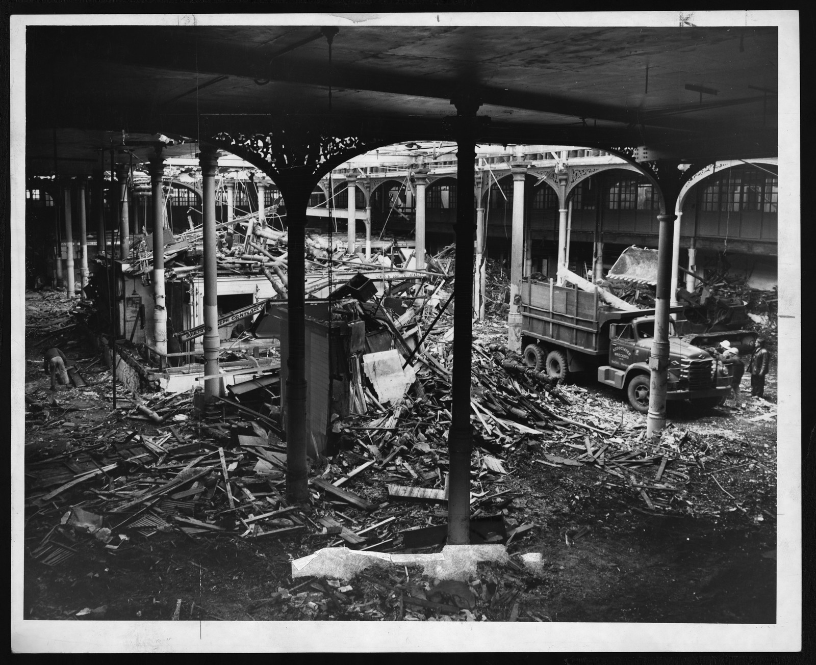 Demolition of iron-columned market hall with dump truck — historic image