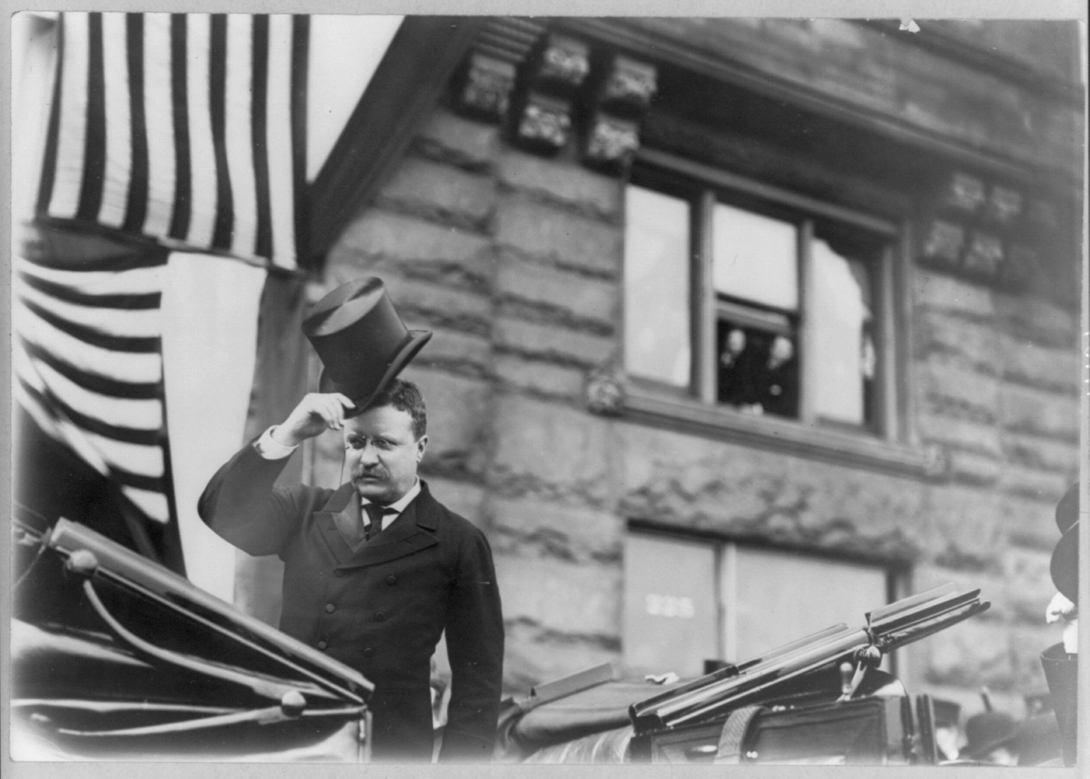 [Theodore Roosevelt, half, standing, in open carriage, facing slightly left] — historic photograph