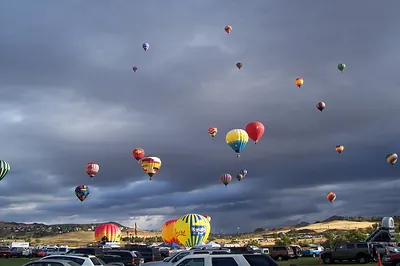 Hot air balloons rising over parking lot at festival