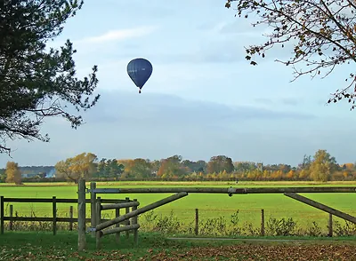 Hot air balloon over a field behind a wooden gate