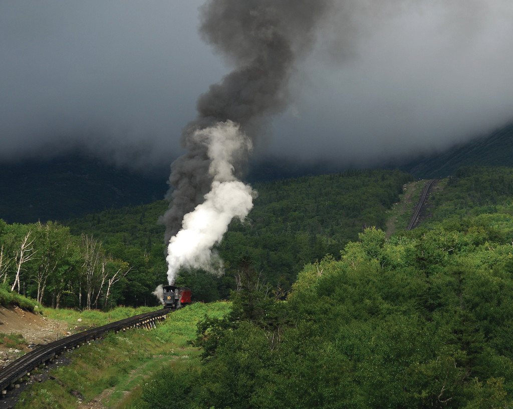 Steam cog train climbing mountainside with smoke plume — historic image
