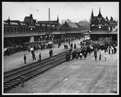 Crowds gathered at a railway terminal with bunting