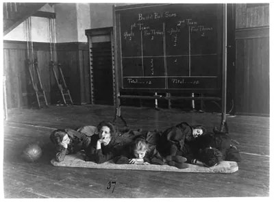 [Five girls lying on mat in gymnasium in front of basketball scoreboard, Western High School, Washington, D.C.]