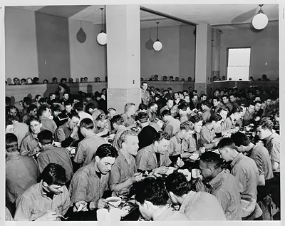 Men eating together in a crowded mess hall