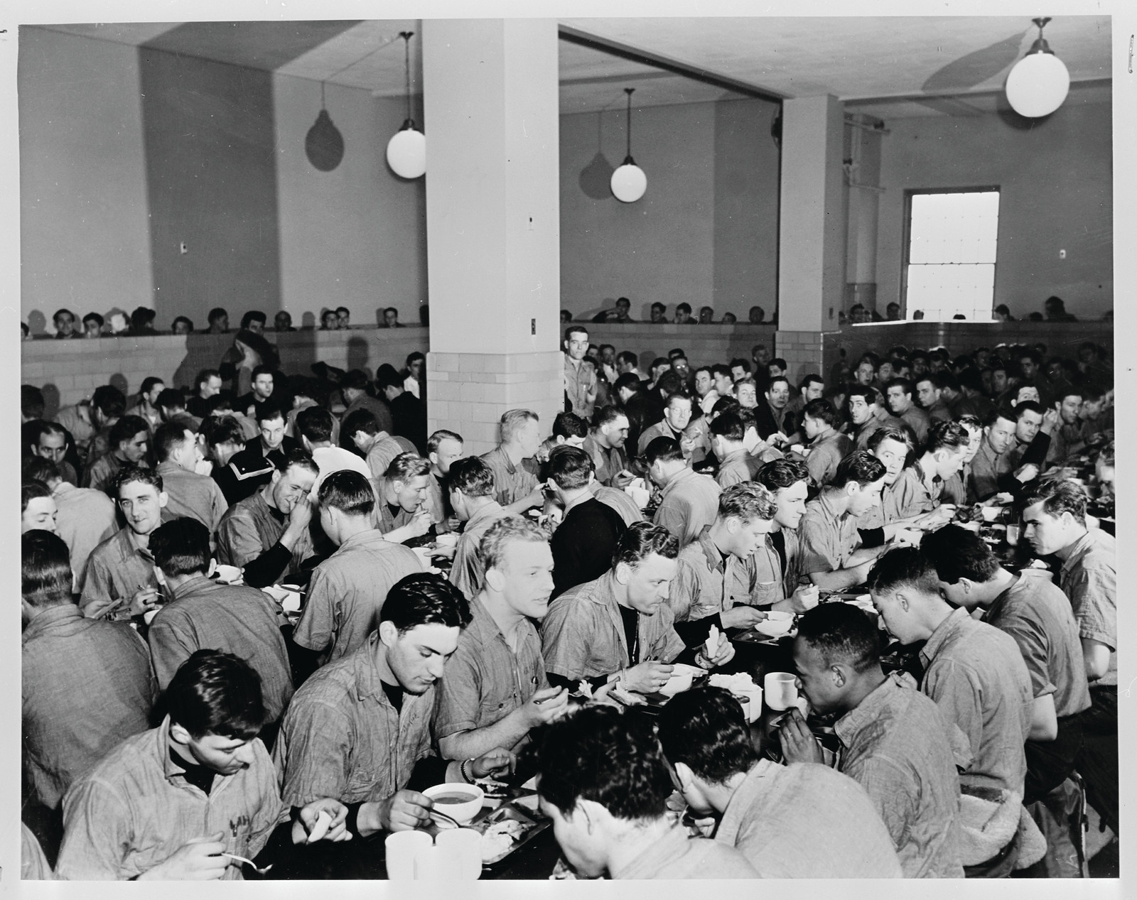 Men eating together in a crowded mess hall — historic image