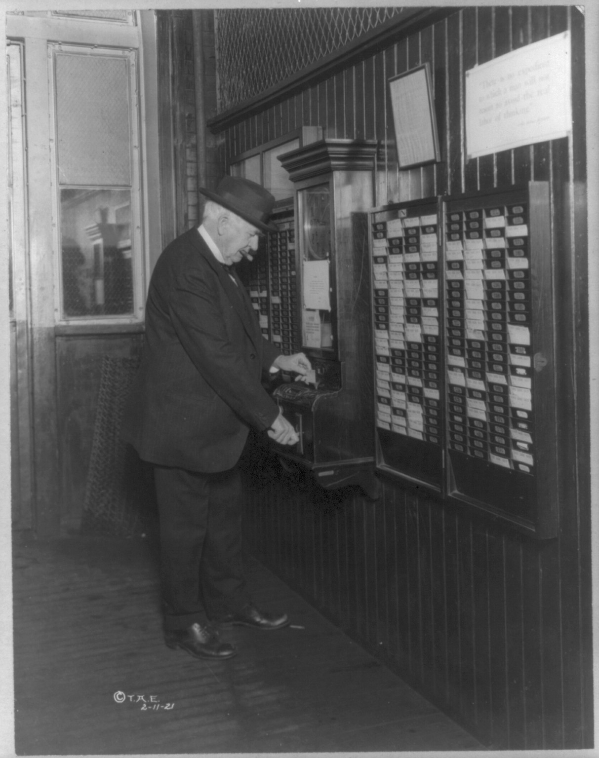 [Thomas Alva Edison, 1847-1931, punching time clock on his 74th birthday anniversary, February 11, 1921, standing, rear view], c1921. — historic photograph
