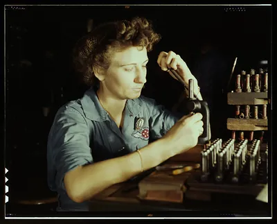 Woman factory worker using a metal tool at a workbench