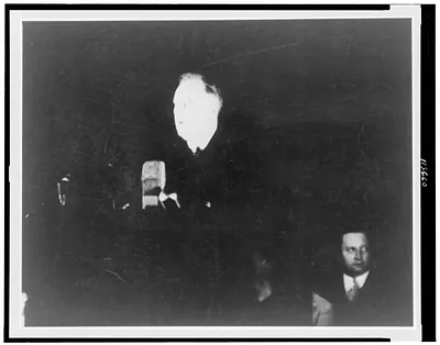[Franklin D. Roosevelt, head-and-shoulders portrait, standing at microphones, facing left]